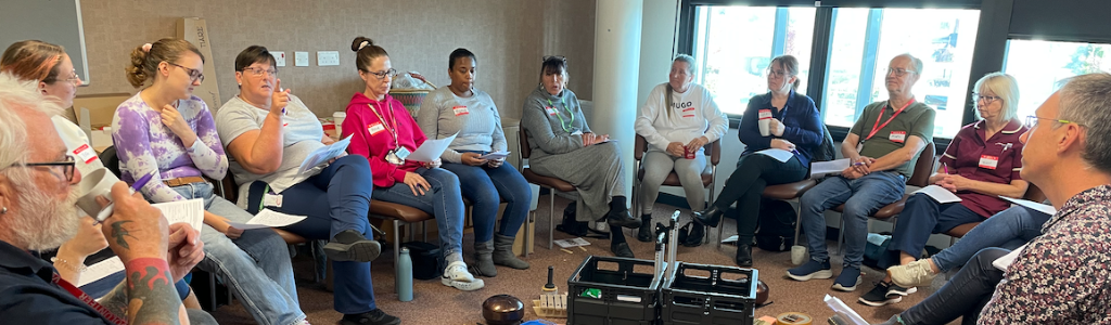 Image of Music Care Training at Mansfield Community Hospital, staff sat in a circle playing instruments